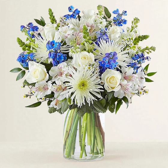 Blue and White Remembrance Bouquet with white spider mums, white roses and blue delphinium on a cream background