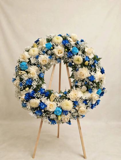 Blue and White Remembrance Wreath with white roses, blue mums and white lilies on a cream background