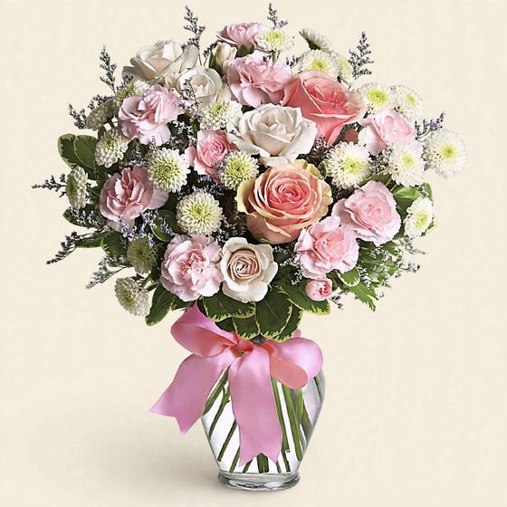 Pink and white roses, pink carnations and white mums in a glass vase with a pink bow