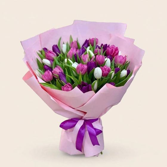 Pink, purple and white tulip bouquet on a cream studio background