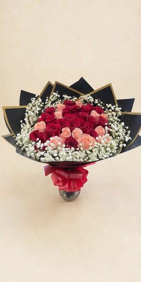 Fifty red and peach roses in black and gold wrap with a red bow