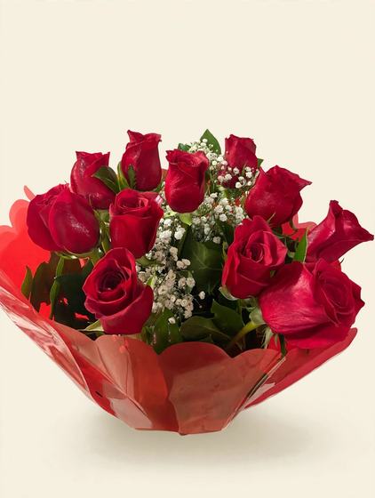 A dozen red roses with baby's breath wrapped in red cellophane on a cream background