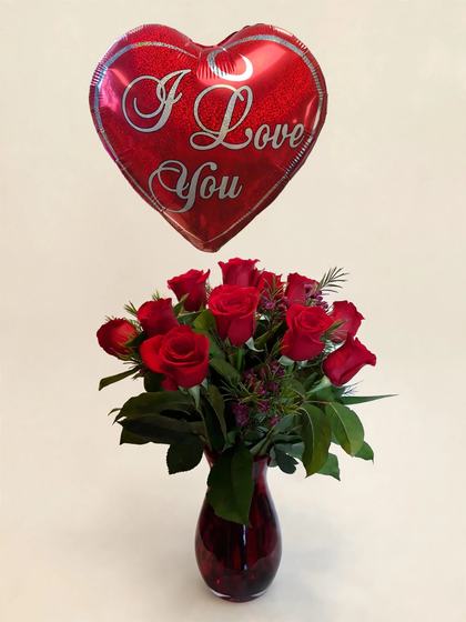 A dozen red roses in a glass vase with an I Love You heart balloon