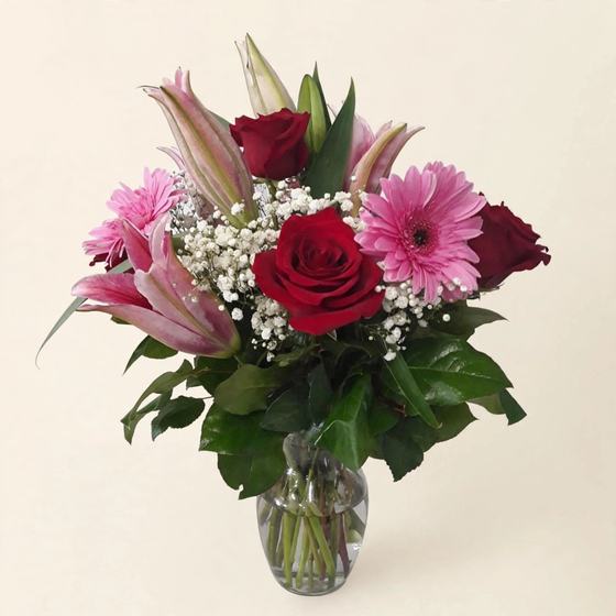 Crimson Lily Bouquet with red roses, pink lilies and pink gerbera daisies on a cream background