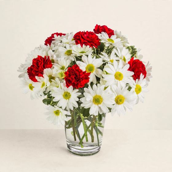 White daisies with red carnations arranged in a clear glass vase