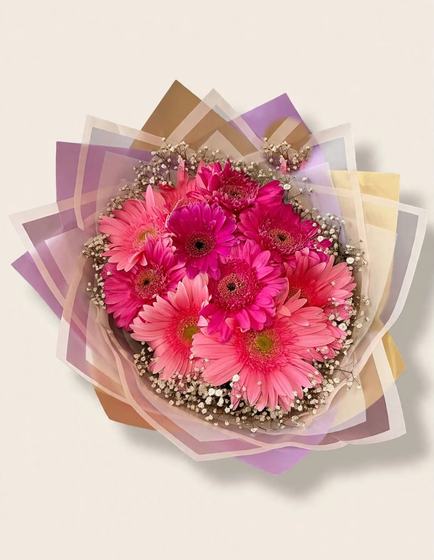 Hot pink gerbera daisies with baby's breath in purple and beige wrap