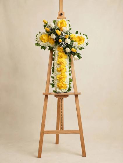 Standing cross spray with yellow and white roses, white chrysanthemums and baby's breath on a cream background
