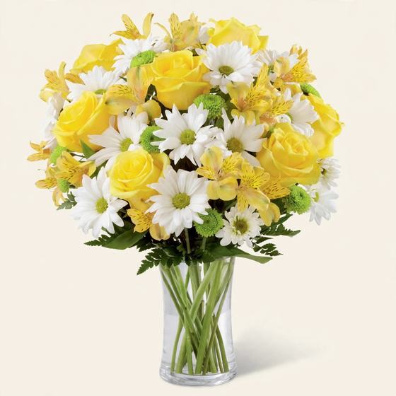 Yellow roses, white daisies and yellow alstroemeria in a clear glass vase