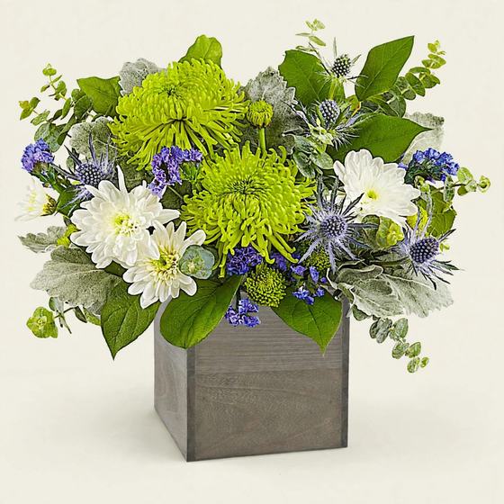 Green mums, white daisies, lavender statice and blue thistle in a gray wooden box
