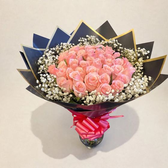 Fifty pink roses with baby’s breath in black and gold wrap with a red bow