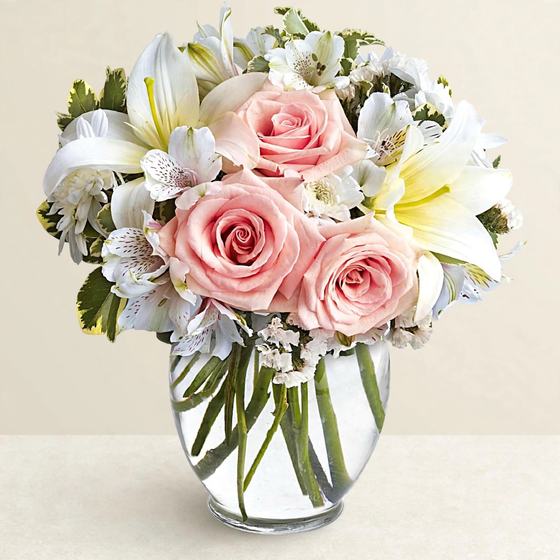 Pink roses, white lilies and white alstroemeria in a glass vase