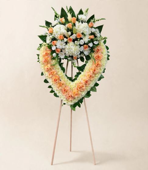 Peach Serenity Heart Wreath of peach roses crowned with white blooms on a cream background