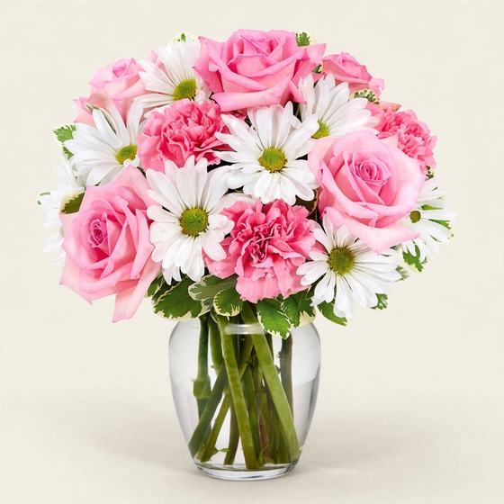 Pink roses, pink carnations and white daisies in a clear glass vase