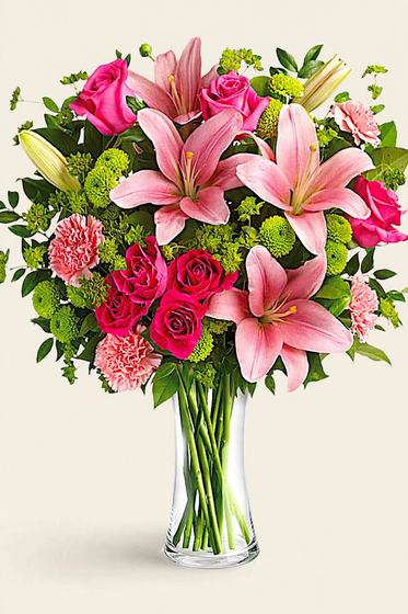 Pink lilies, hot pink roses, pink carnations and green mums in a glass vase