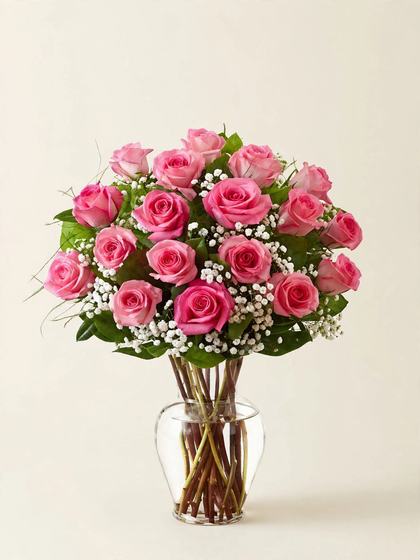Twenty-four pink roses with baby's breath in a glass vase on a cream background