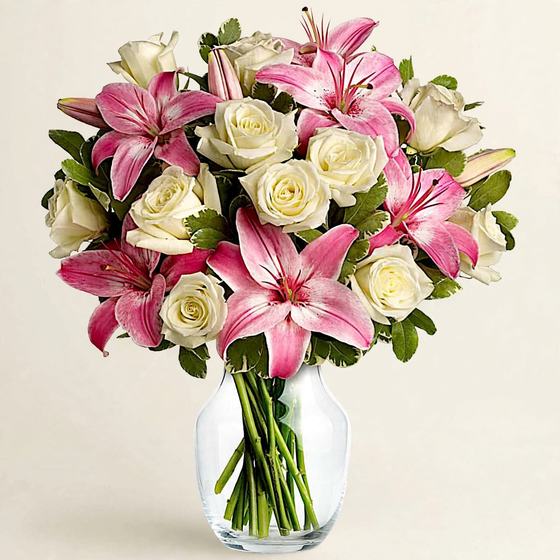 Pink stargazer lilies with white and cream roses in a glass vase