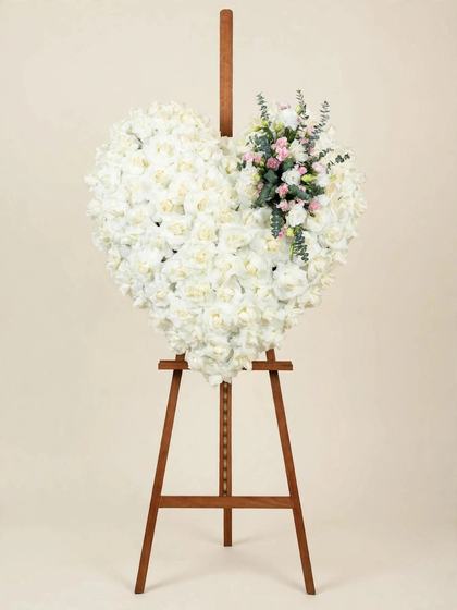Large heart of white roses with pink spray roses and eucalyptus mounted on a tall wooden easel