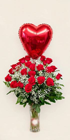 Two dozen red roses with baby's breath and a complete red heart balloon in a clear glass vase on a cream background