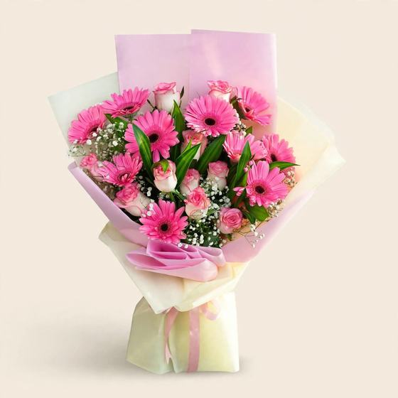 Pink gerberas and pink roses with baby's breath in pink and cream wrap on a cream background