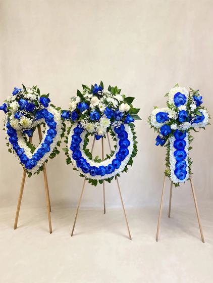 Royal Blue Funeral Set with a blue and white heart wreath, a round blue and white wreath and a blue and white cross on tall wooden easels