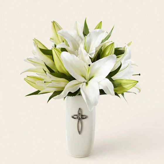 Sacred White Lily Bouquet with white lilies in a white vase adorned with a silver cross