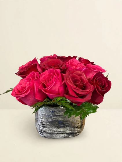 A dozen hot pink roses in a textured silver pot