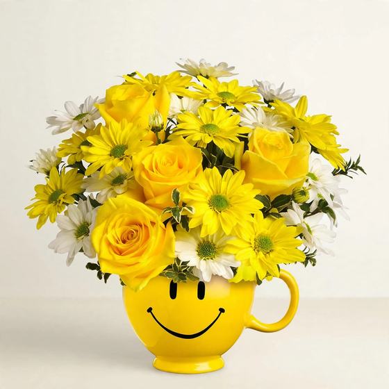 Yellow roses and yellow and white daisies arranged in a yellow smiley-face mug on a cream background
