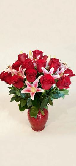 Red roses and pink and white stargazer lilies in a red vase