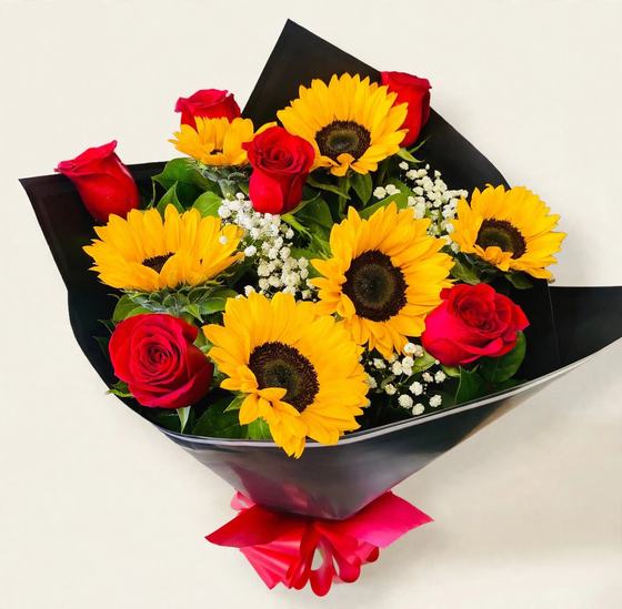 A dozen sunflowers and red roses with baby's breath in black wrap with a red ribbon on a cream background