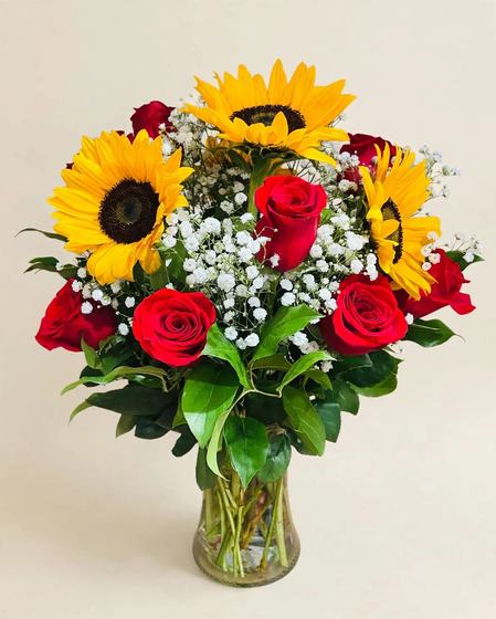 Sunflowers and red roses with white baby's breath in a clear glass vase