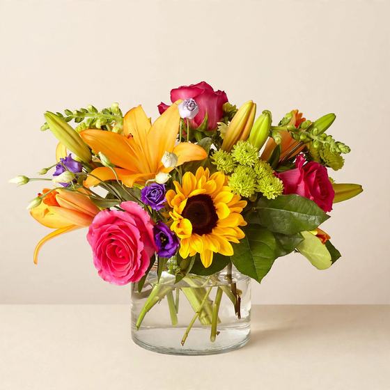 Sunshine Rainbow Bouquet with orange lilies, sunflower and pink roses on a cream background