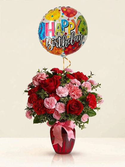 Red roses and pink and red carnations in a red vase with a pink bow and Happy Birthday balloon