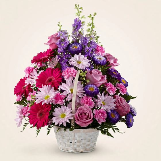 Vibrant Remembrance Basket with hot pink gerbera daisies, pink daisies and purple blooms on a cream background